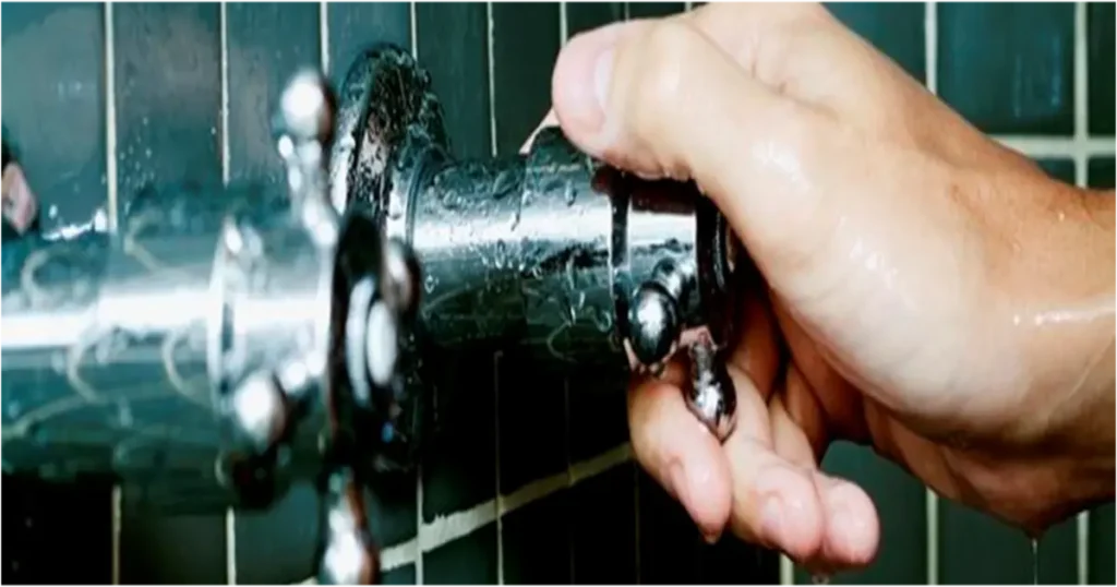 Fechando registro de chuveiro para ajudar na redução do consumo de energia.